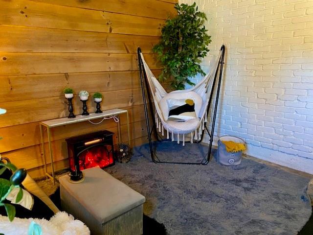 living area featuring carpet and brick wall