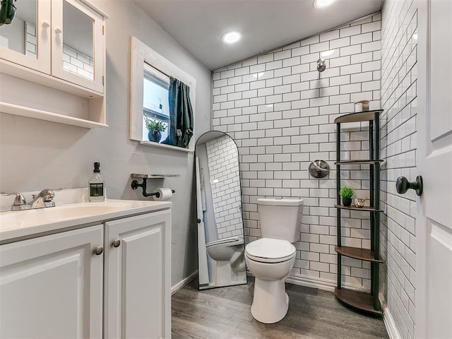 bathroom with a bidet, tile walls, vanity, wood-type flooring, and toilet