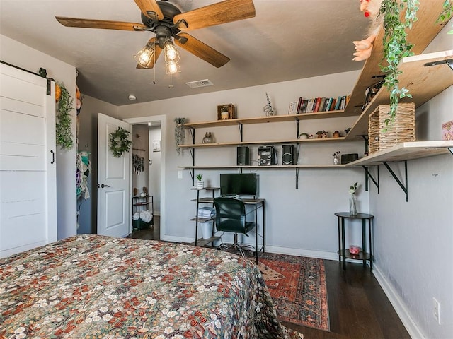 unfurnished bedroom with ceiling fan, a barn door, and dark hardwood / wood-style flooring