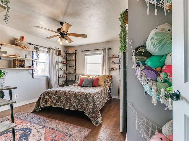 bedroom featuring dark wood-type flooring, ceiling fan, and multiple windows