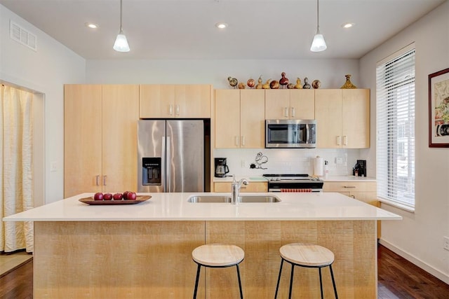 kitchen featuring stainless steel appliances, sink, light brown cabinets, and decorative light fixtures