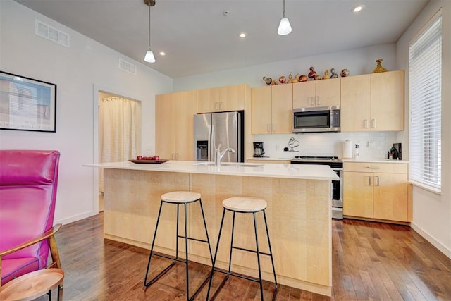 kitchen with pendant lighting, light brown cabinetry, stainless steel appliances, and sink