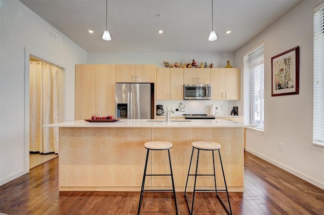 kitchen featuring appliances with stainless steel finishes, sink, a kitchen island with sink, and light brown cabinetry