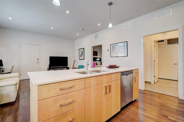 kitchen featuring sink, a center island with sink, light brown cabinets, dishwasher, and pendant lighting