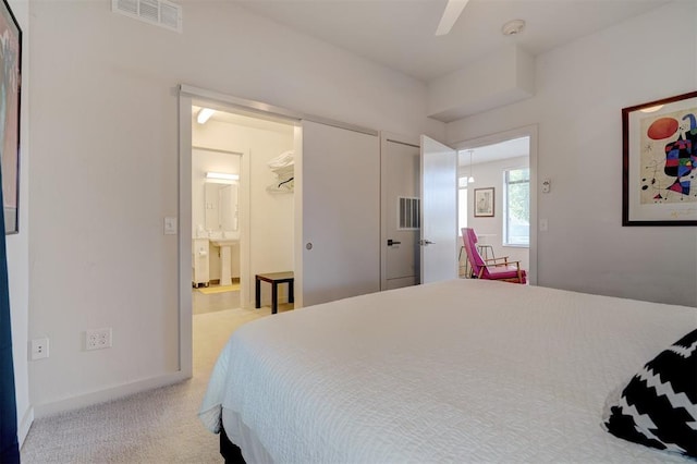 bedroom featuring light carpet, ceiling fan, and ensuite bathroom