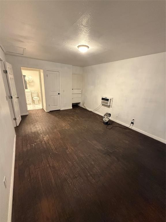 unfurnished room with dark wood-style floors, attic access, baseboards, and a wall mounted AC