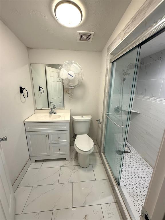 full bath with visible vents, toilet, marble finish floor, vanity, and a shower stall