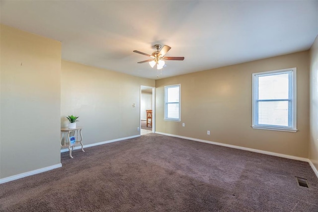 empty room with ceiling fan and dark colored carpet