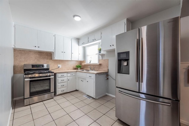 kitchen with light tile patterned flooring, sink, white cabinetry, appliances with stainless steel finishes, and backsplash