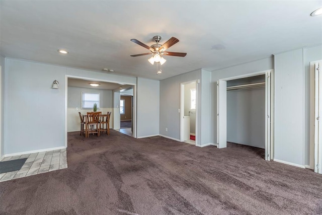 interior space featuring ceiling fan and dark carpet