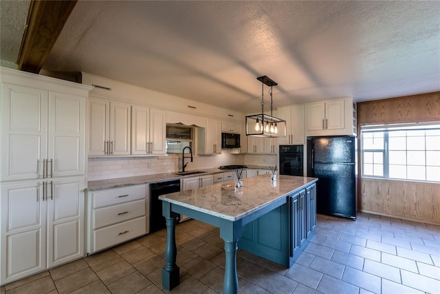 kitchen featuring sink, decorative light fixtures, a kitchen breakfast bar, an island with sink, and black appliances