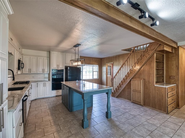 kitchen featuring a kitchen island, decorative light fixtures, a kitchen breakfast bar, black appliances, and light stone countertops