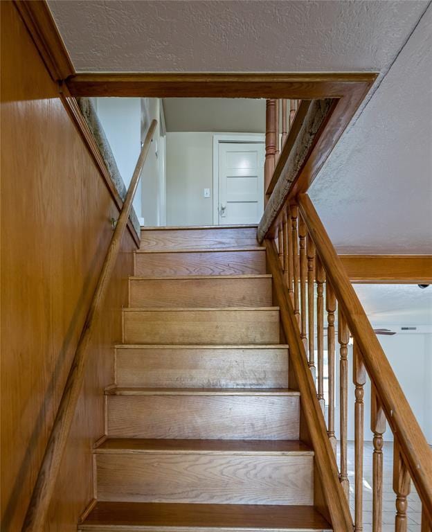 staircase featuring wood-type flooring and a textured ceiling