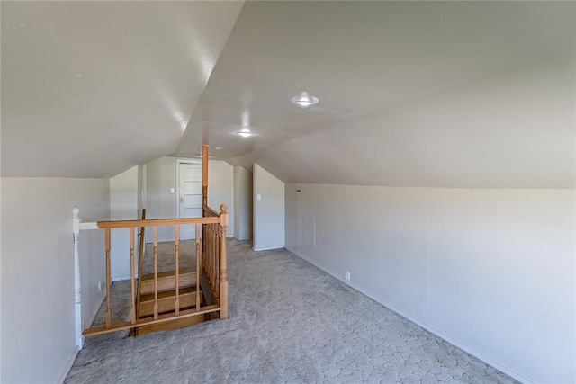 bonus room with lofted ceiling and light carpet