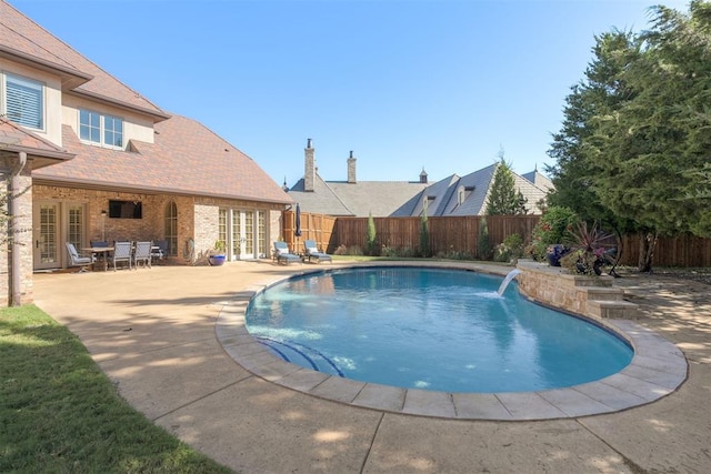 view of pool with a patio area, pool water feature, and french doors