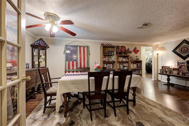 dining space with ceiling fan, ornamental molding, hardwood / wood-style floors, and a textured ceiling