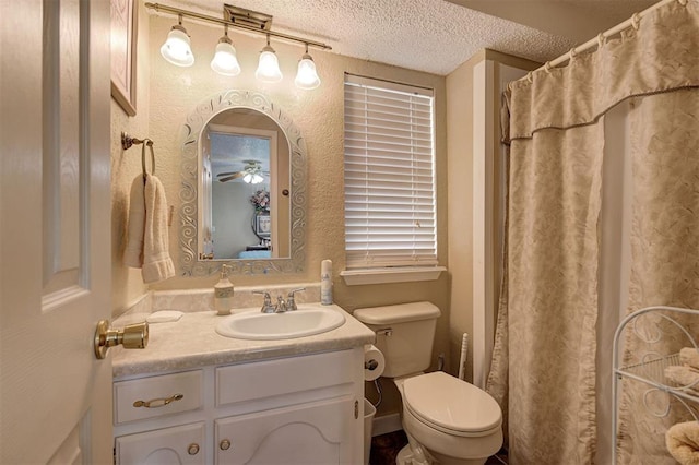 bathroom with curtained shower, vanity, ceiling fan, toilet, and a textured ceiling