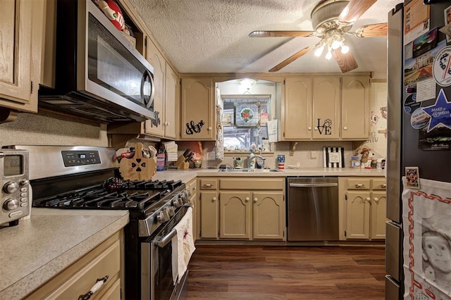 kitchen with sink, a textured ceiling, appliances with stainless steel finishes, dark hardwood / wood-style floors, and cream cabinetry