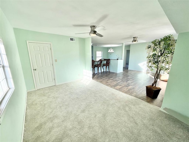 unfurnished room featuring ceiling fan with notable chandelier and carpet flooring