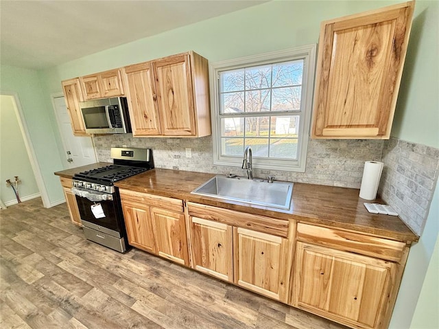 kitchen featuring appliances with stainless steel finishes, light hardwood / wood-style floors, sink, and decorative backsplash