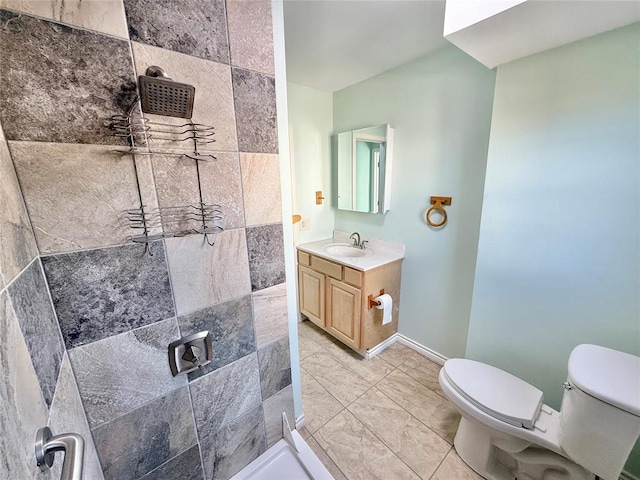 bathroom with vanity, tiled shower, and toilet