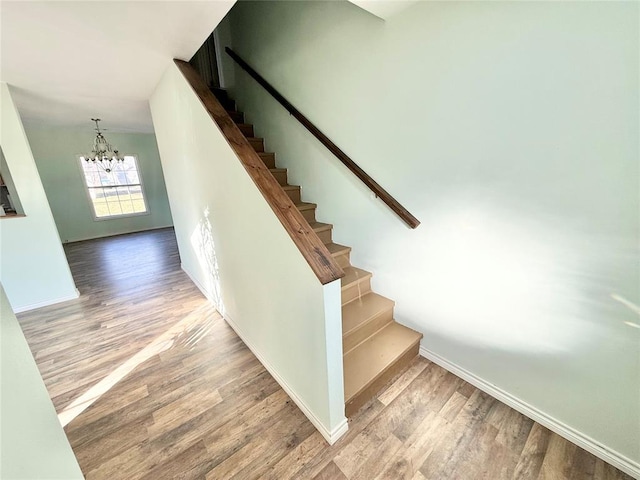 stairs featuring hardwood / wood-style floors and a notable chandelier