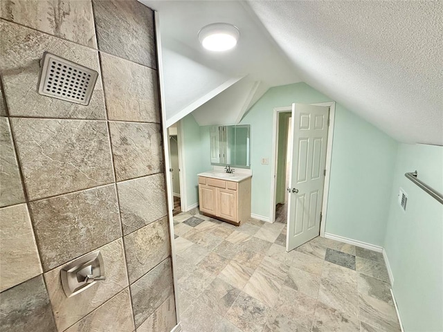 bathroom featuring vanity, lofted ceiling, and a textured ceiling