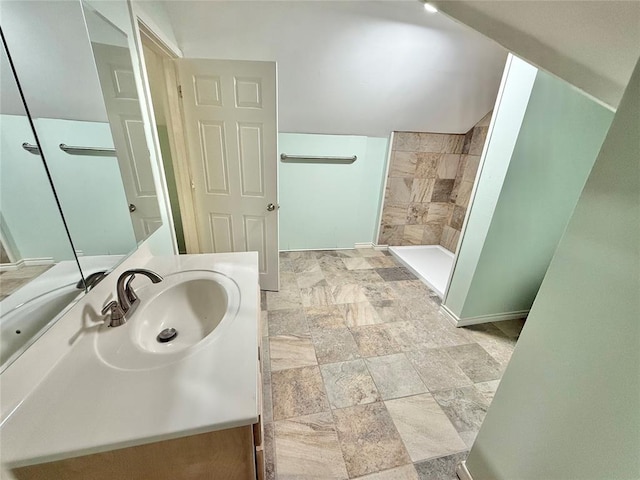 bathroom featuring walk in shower, vanity, and vaulted ceiling