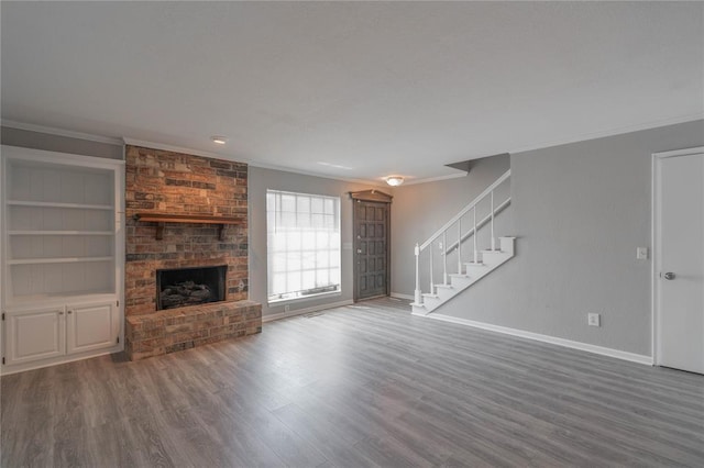 unfurnished living room featuring ornamental molding, a brick fireplace, wood-type flooring, and built in features