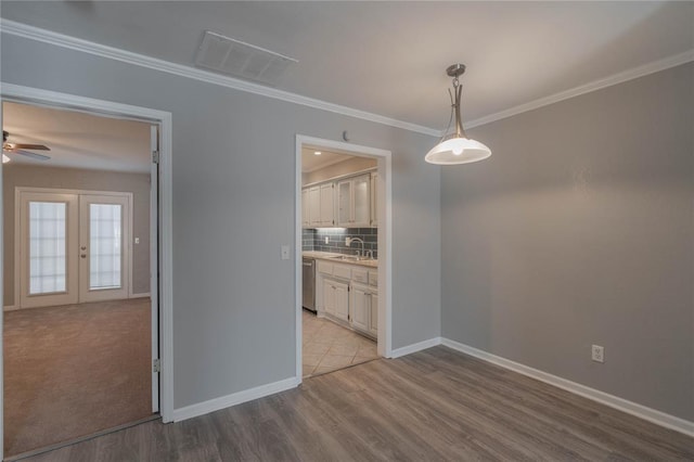 unfurnished dining area featuring sink, ornamental molding, light hardwood / wood-style floors, and french doors