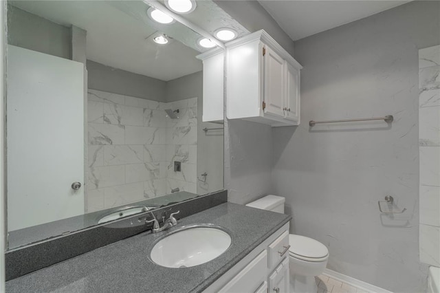 bathroom with tiled shower, vanity, and toilet