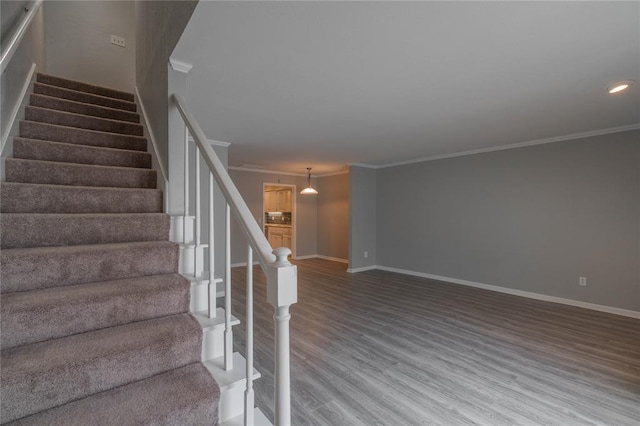 stairway with ornamental molding and hardwood / wood-style floors