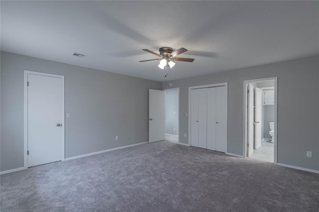 unfurnished bedroom featuring ceiling fan, light colored carpet, and ensuite bath