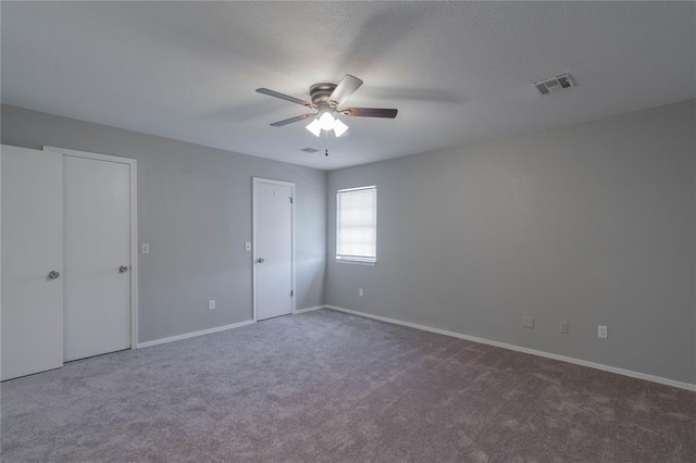 unfurnished bedroom with ceiling fan, dark carpet, and two closets