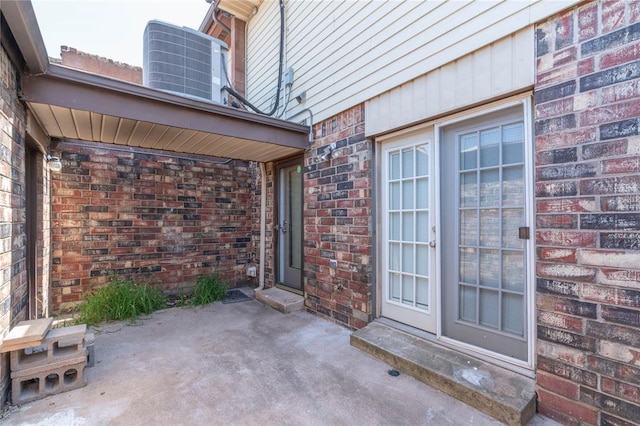 view of exterior entry with a patio area and central air condition unit