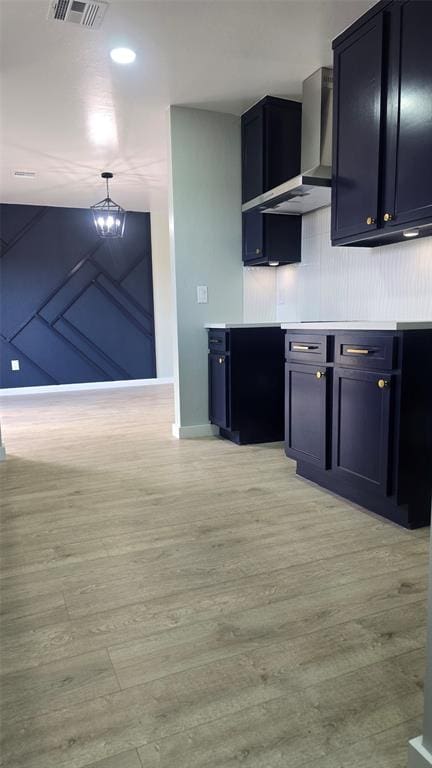 kitchen featuring hanging light fixtures, wall chimney exhaust hood, and light wood-type flooring