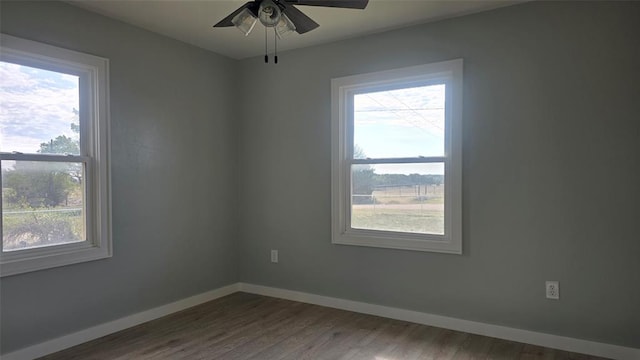 empty room with ceiling fan, wood-type flooring, and a wealth of natural light