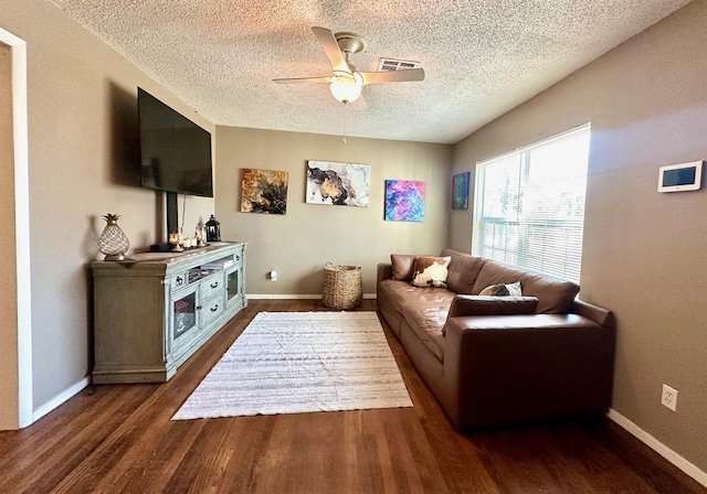 living room featuring visible vents, a textured ceiling, baseboards, ceiling fan, and dark wood-style flooring