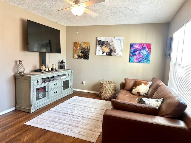 living area featuring ceiling fan, a textured ceiling, baseboards, and dark wood-style flooring