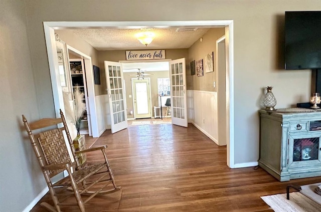 entryway with wood finished floors, french doors, baseboards, and a textured ceiling