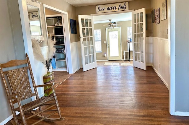 entryway featuring wainscoting, french doors, radiator, and wood finished floors