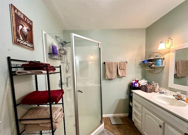 bathroom with baseboards, a textured ceiling, a stall shower, and vanity