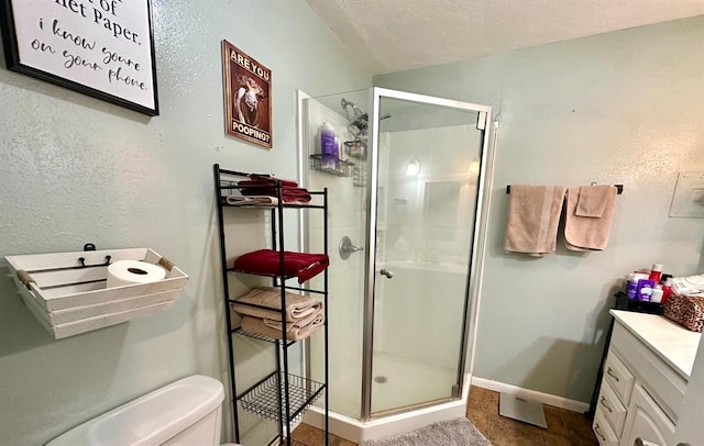 full bath with vanity, baseboards, a shower stall, a textured ceiling, and toilet