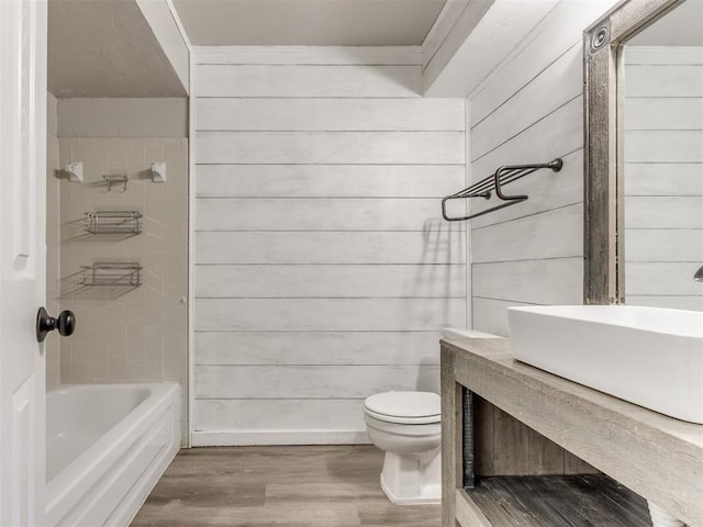 720 Cottonwood Dr, Moore, OK 73160 - bathroom featuring wood finished floors, toilet, tub / shower combination, vanity, and wood walls