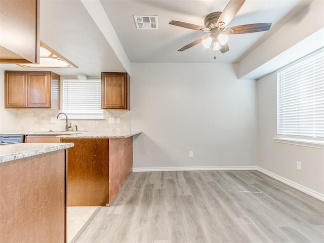 720 Cottonwood Dr, Moore, OK 73160 - kitchen with a sink, brown cabinets, a ceiling fan, light wood finished floors, and backsplash