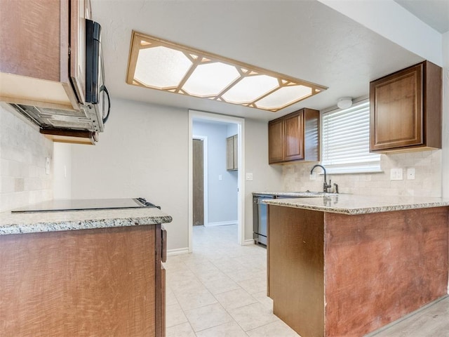 720 Cottonwood Dr, Moore, OK 73160 - kitchen with appliances with stainless steel finishes, decorative backsplash, a peninsula, a sink, and baseboards