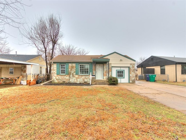 ranch-style home featuring a garage, central AC unit, and a front yard