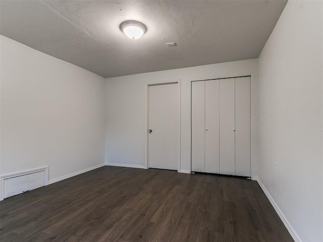 unfurnished bedroom featuring dark hardwood / wood-style flooring and a closet