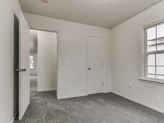 unfurnished bedroom with multiple windows and dark carpet