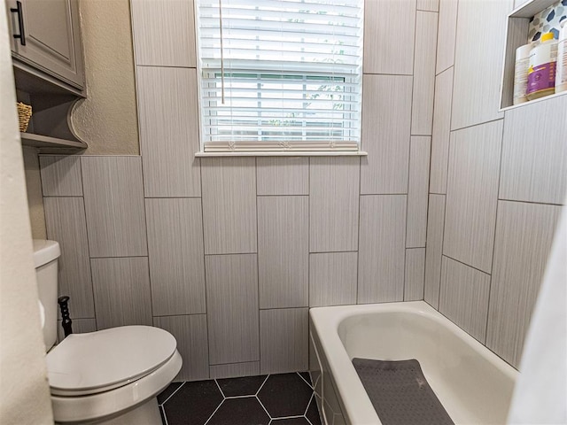 bathroom with toilet, tile patterned flooring, tile walls, and a washtub